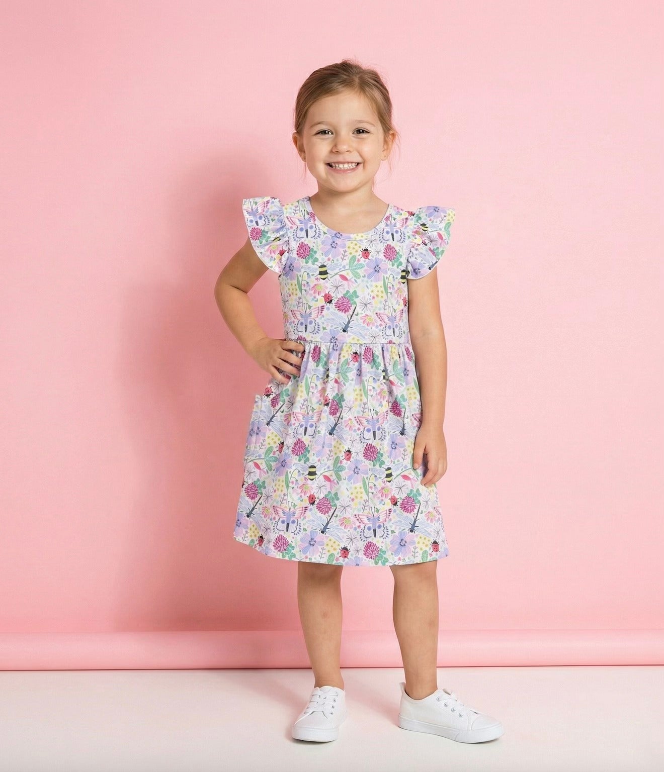 A smiling girl in a lightweight summer girl dress with colorful patterns, perfect for sunny playtime.